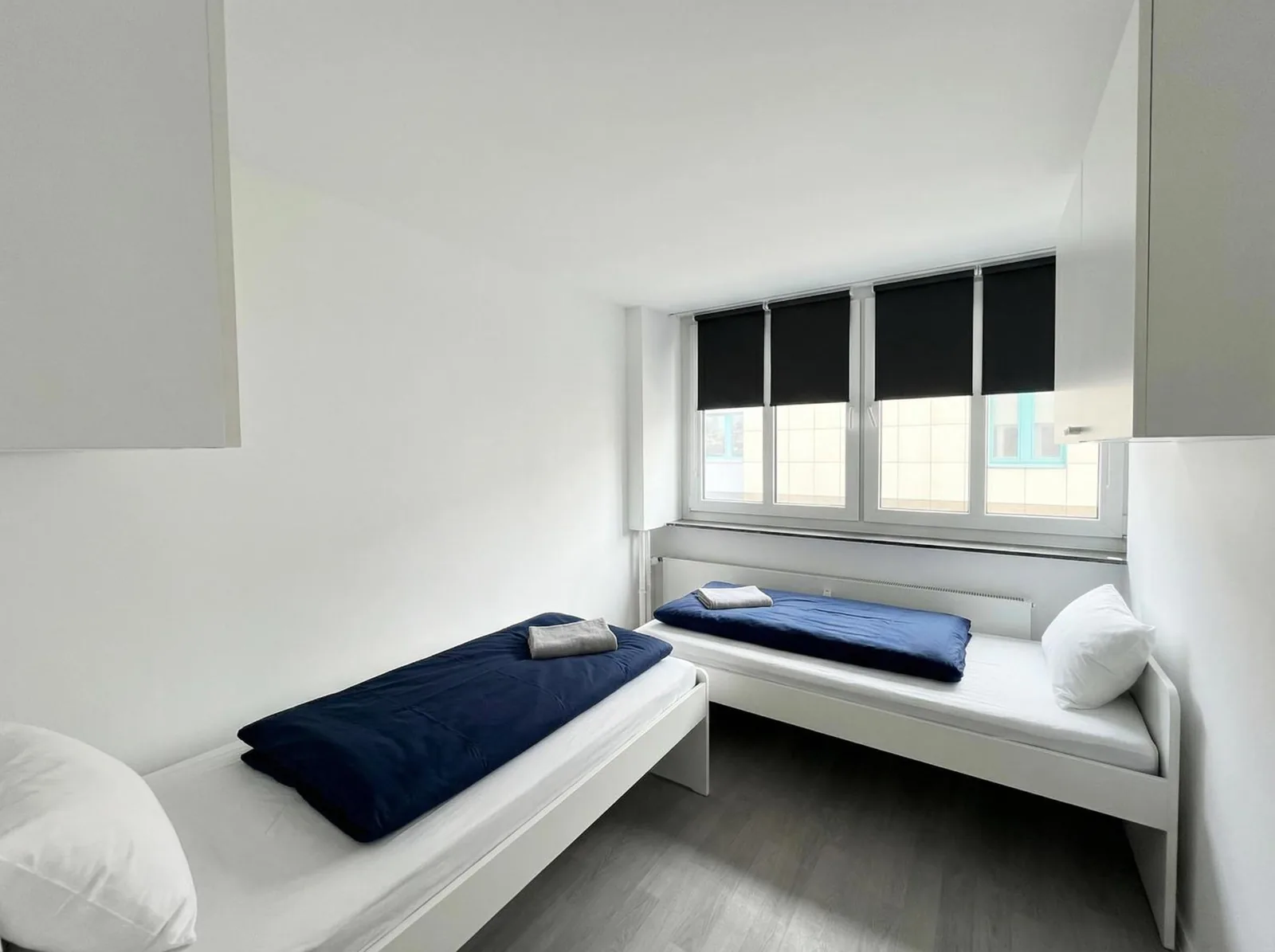 Zweibettzimmer mit zwei Einzelbetten und dunkelblauer Bettwäsche am Rheinlanddamm 6