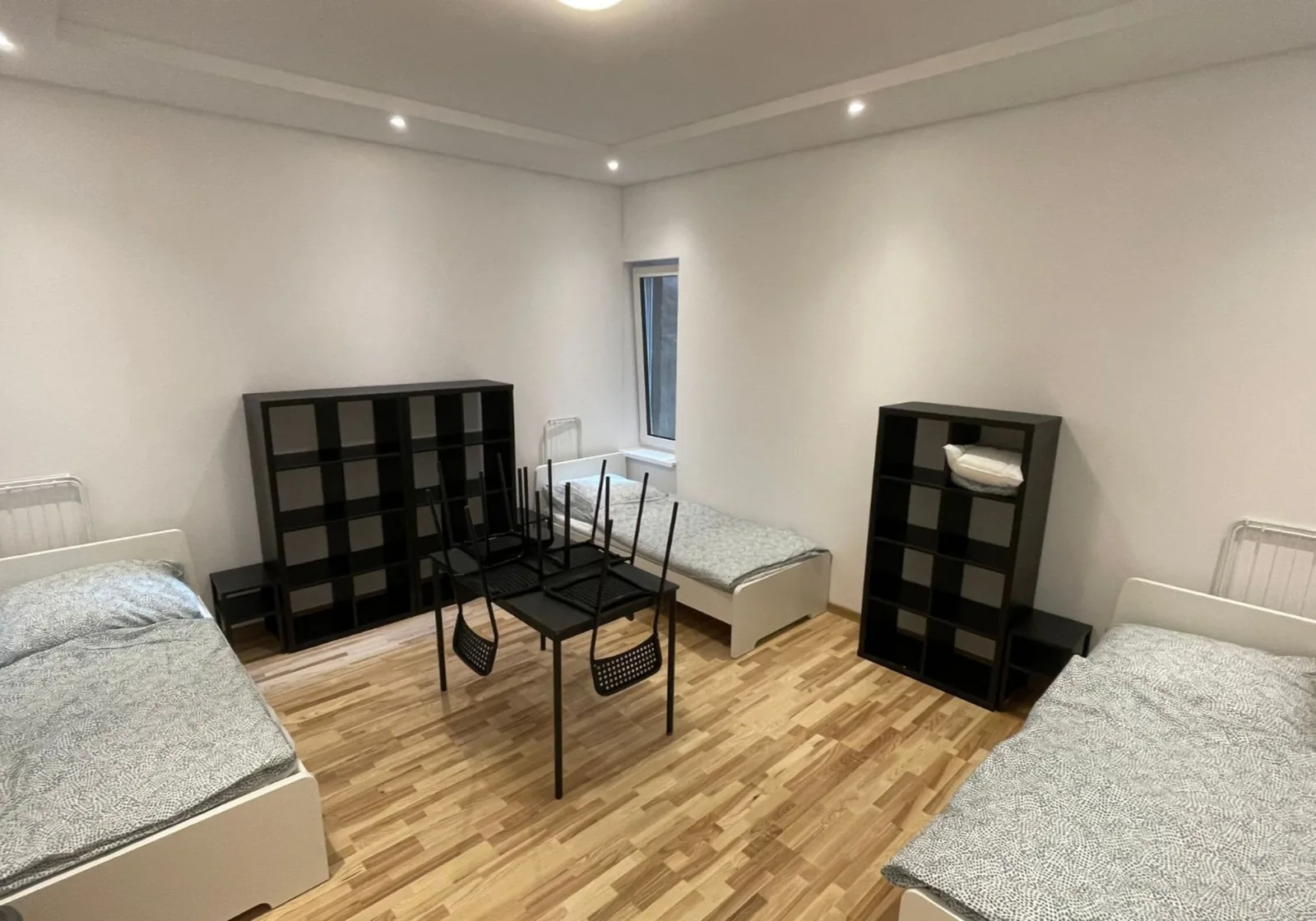 Zweibettzimmer mit zwei Einzelbetten, Regalen und Esstisch