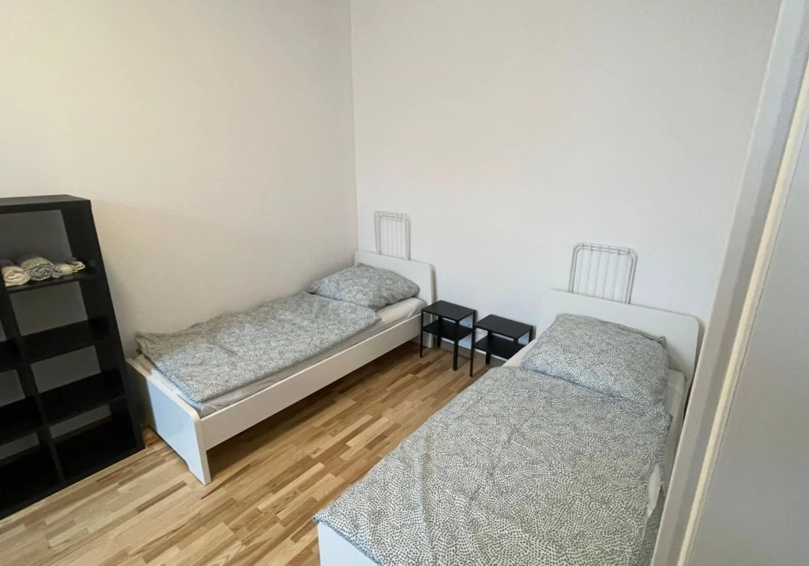 Helles Zweibettzimmer mit weißen Einzelbetten und Nachttischen