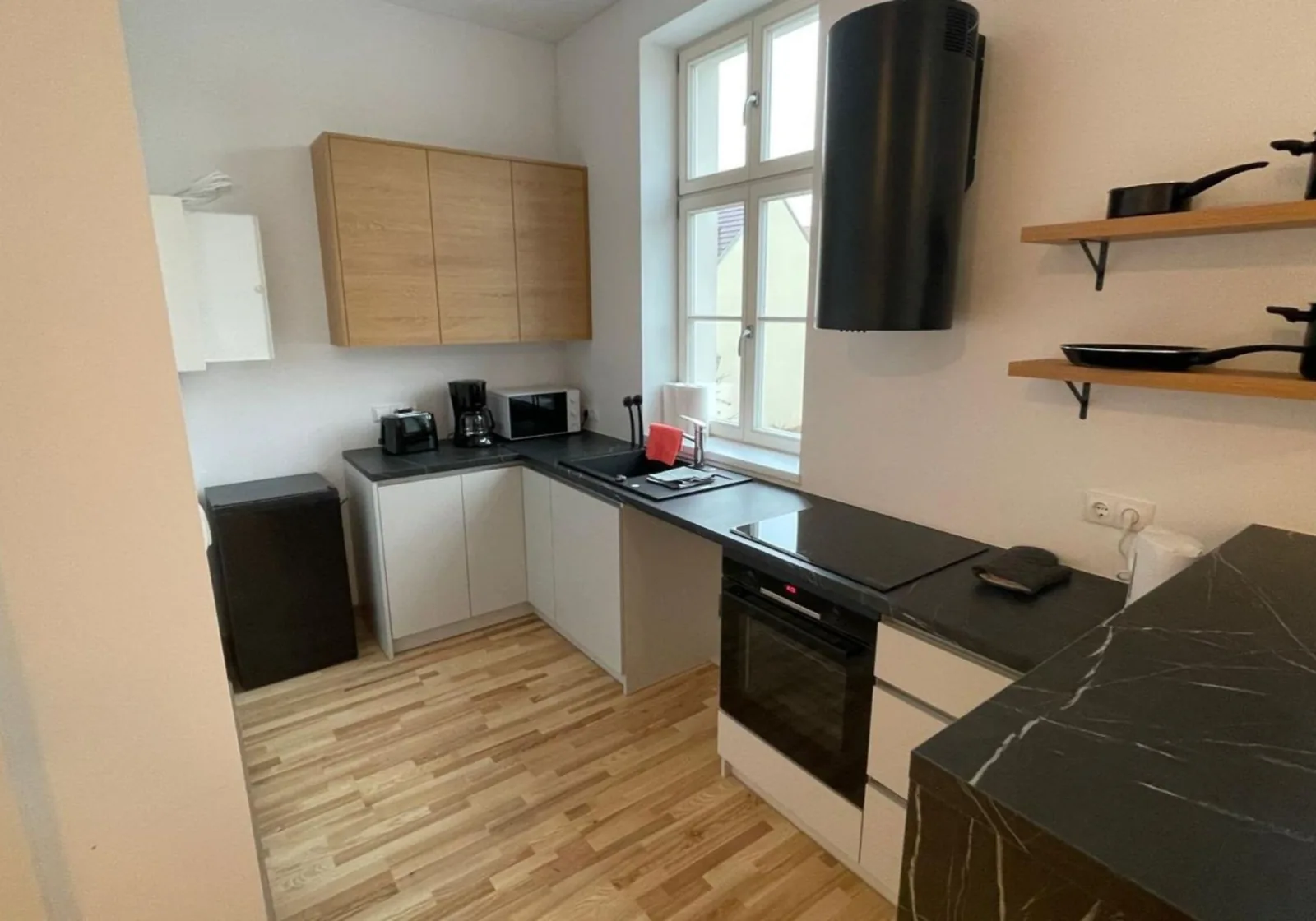 Küche mit Holzfronten, Backofen, Mikrowelle und Kaffeemaschine